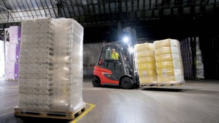Gasstapler H20 - die neue Generation Linde Gabelstapler transportiert in dunkler Halle mit Licht
