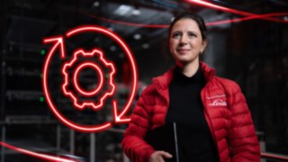Mitarbeiterin von Linde Material Handling in einer Lagerhalle mit rotem LED-Symbol eines Zahnrads für Automatisierung im Hintergrund.