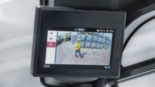 Blick auf das Display, auf dem die Kameraansicht der Reverse Assist Camera zu sehen ist, die einen Fußgänger im Rückwärtsraum zeigt.