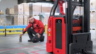 Ein Mitarbeiter von Linde MH kniet vor einem L-MATIC und prüft, dass alles stimmt.