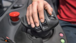 Hand des Staplerfahrers liegt auf dem Multifunktionshebel von Linde Material Handling